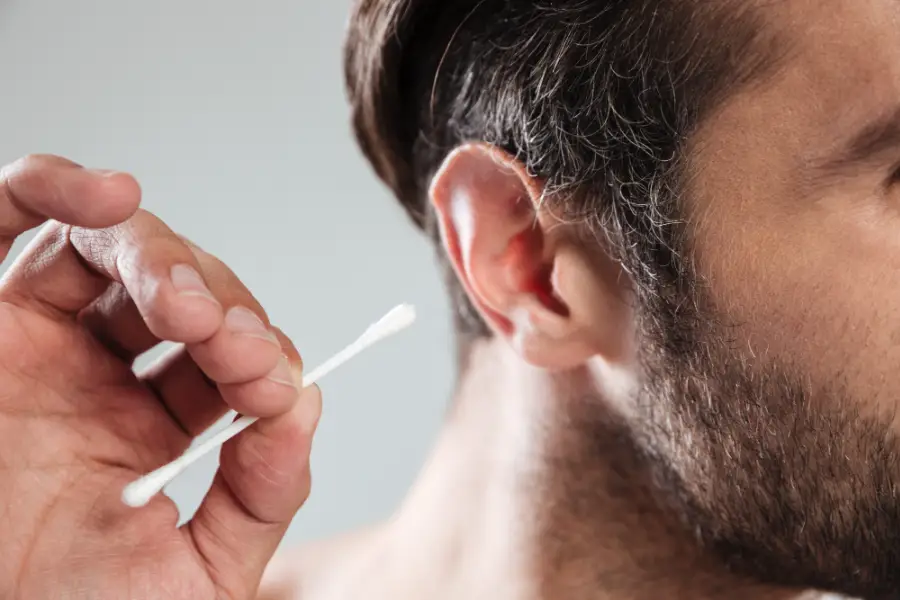 Man using cotton bud to remove earwax